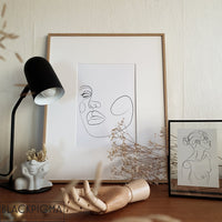 Affiche d'un visage de femme en line art, présentée dans un décor moderne, dans un cadre couleur bois avec un passe-partout.