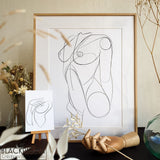 Illustration d'une femme nue dessinée en line art, dans un cadre en bois.