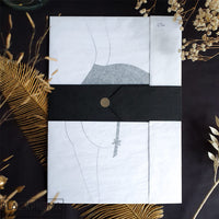 Emballage cadeau de l'affiche minimaliste Elsa, papier de soie blanc et ceinture de soie noire, boutique Blackpigma.