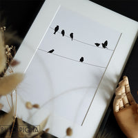 Encadrement et présentation de l'affiche des petits oiseaux, dessin en noir et blanc d'oiseaux sur un fil.